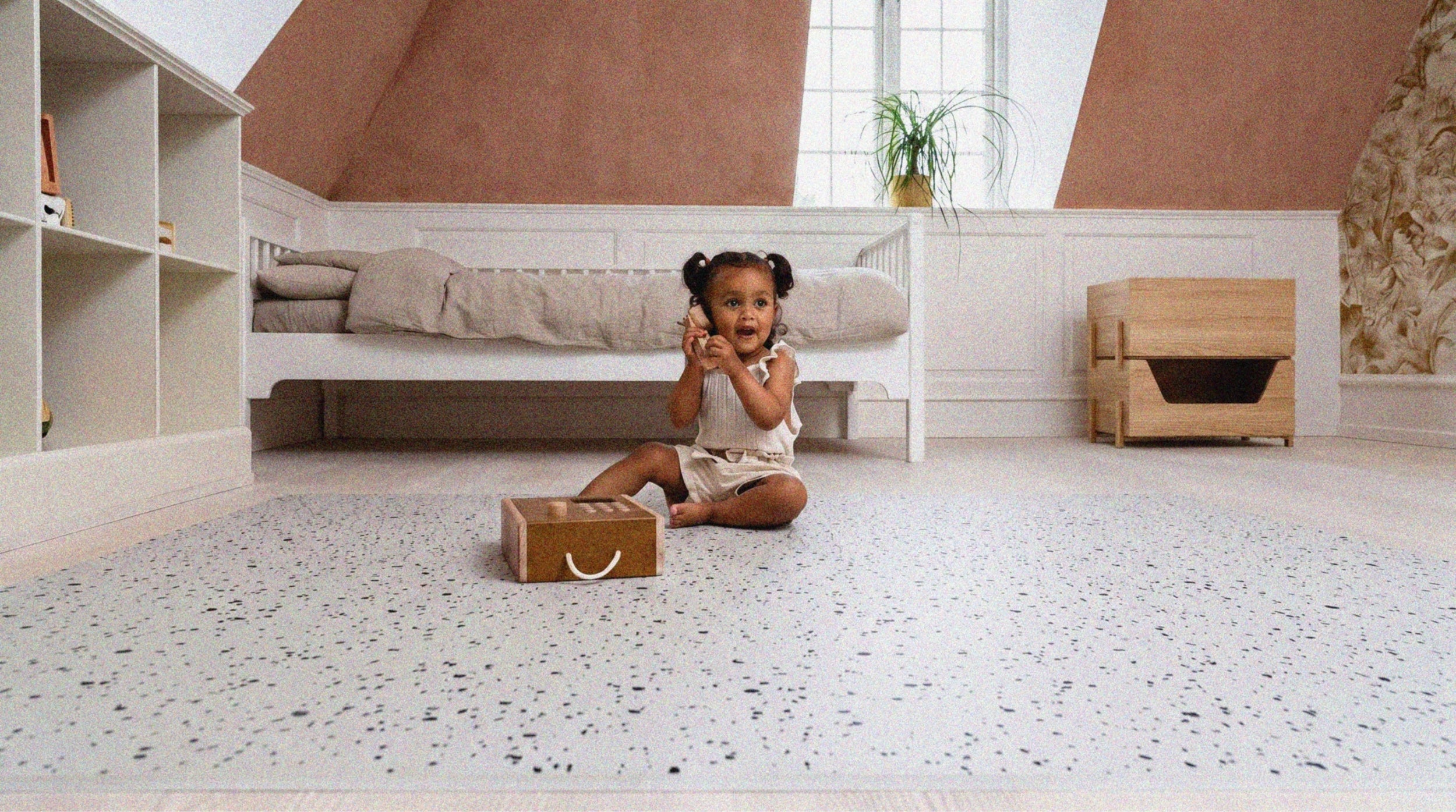 Girl talking on a toy phone atop her non-toxic interlocking terrazzo phone play mat 